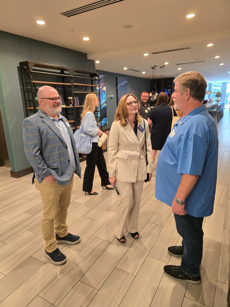 Kelly Grappe talks with attendees before addressing an Arkansas AFL-CIO gathering, standing in conversation inside the event venue.