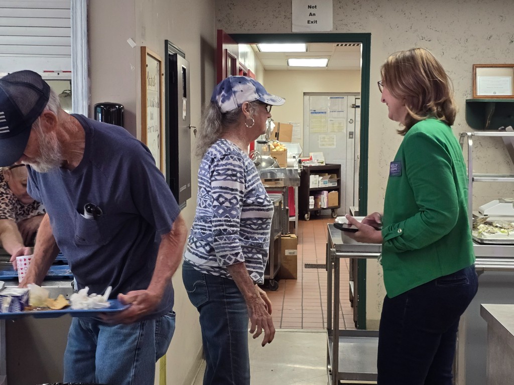 Kelly Grappe for Arkansas Secretary of State — campaign photo Kelly Grappe, candidate for Arkansas Secretary of State. Kelly Grappe talks with community members in a cafeteria line during a local gathering.