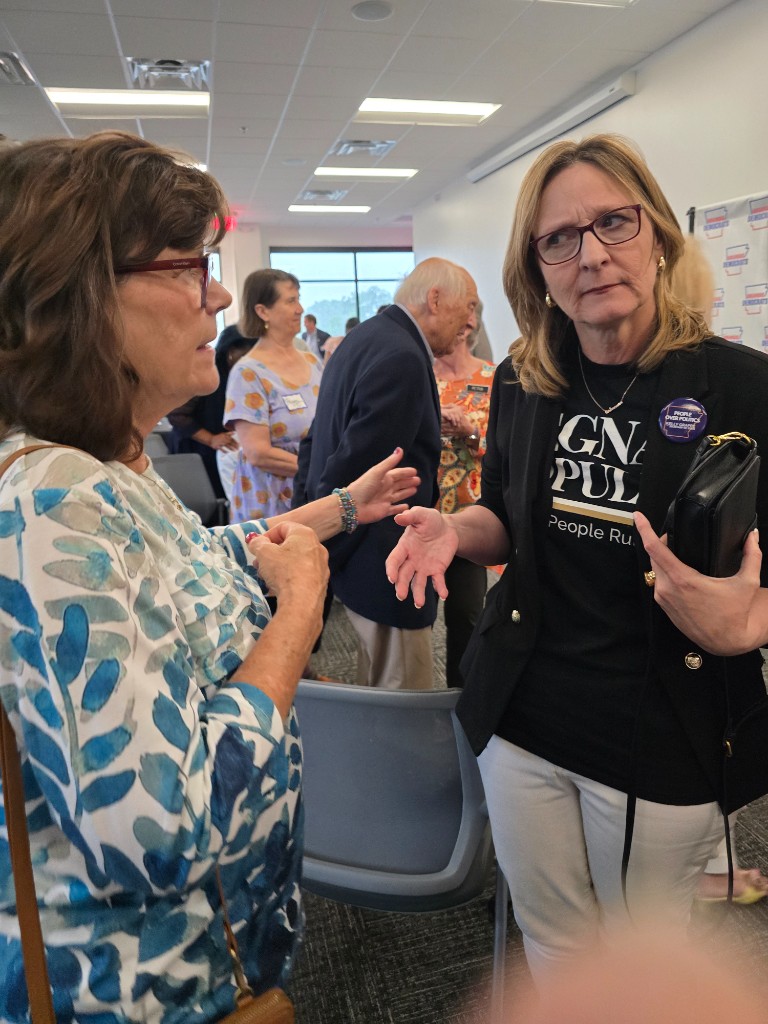 Kelly Grappe for Arkansas Secretary of State — campaign photo Kelly Grappe, candidate for Arkansas Secretary of State. Kelly Grappe listens to a community member during an indoor civic meeting.