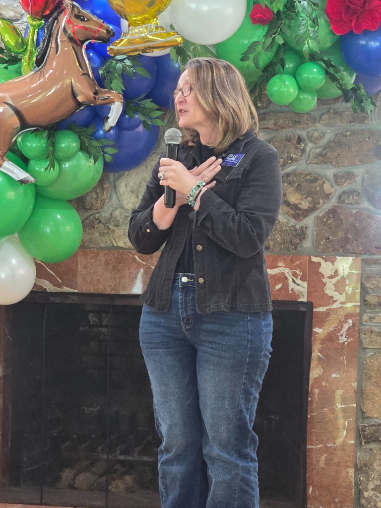 Kelly Grappe for Arkansas Secretary of State — speaks to a community gathering with a microphone Kelly Grappe, candidate for Arkansas Secretary of State, speaks to a community gathering with a microphone.