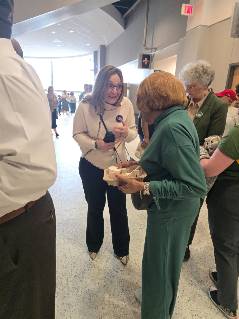 Kelly Grappe for Arkansas Secretary of State — talks with a neighbor in a community hallway Kelly Grappe, candidate for Arkansas Secretary of State, talks with a neighbor in a community hallway.