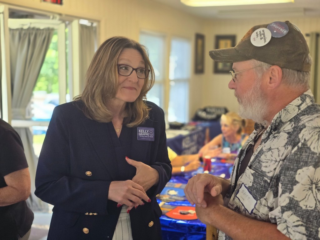 Kelly Grappe for Arkansas Secretary of State — campaign photo Kelly Grappe, candidate for Arkansas Secretary of State. Kelly Grappe talks with a community member at an indoor meet-and-greet.