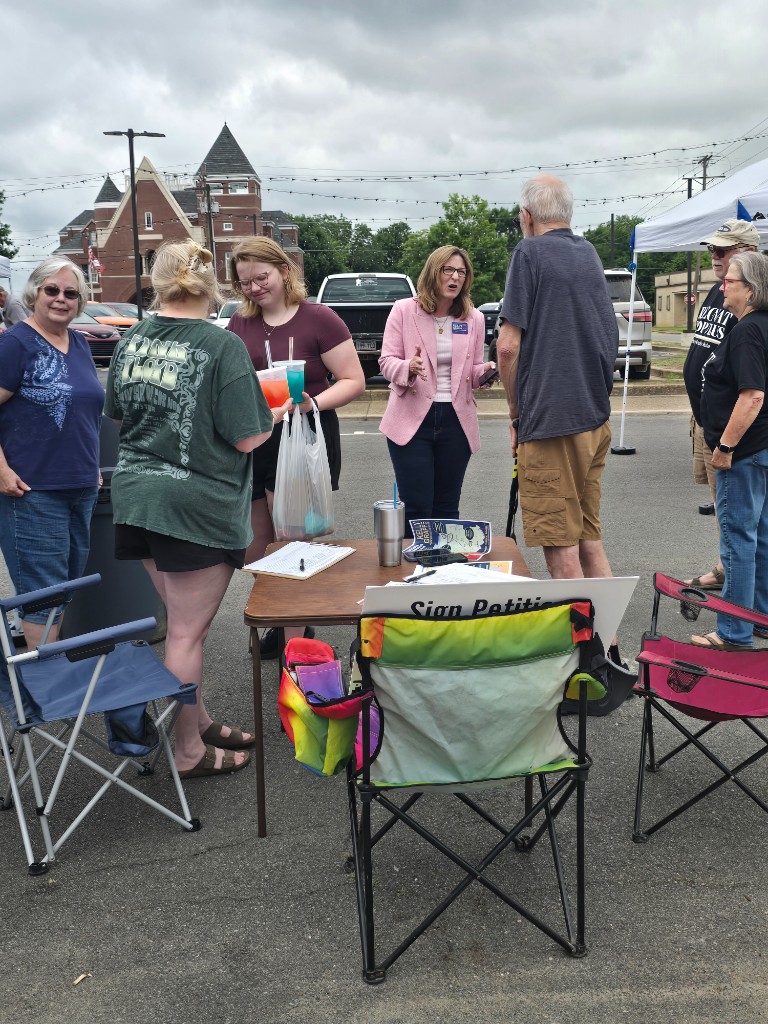 Kelly Grappe for Arkansas Secretary of State — campaign photo Kelly Grappe, candidate for Arkansas Secretary of State. Kelly Grappe talks with community members around an outdoor petition table.