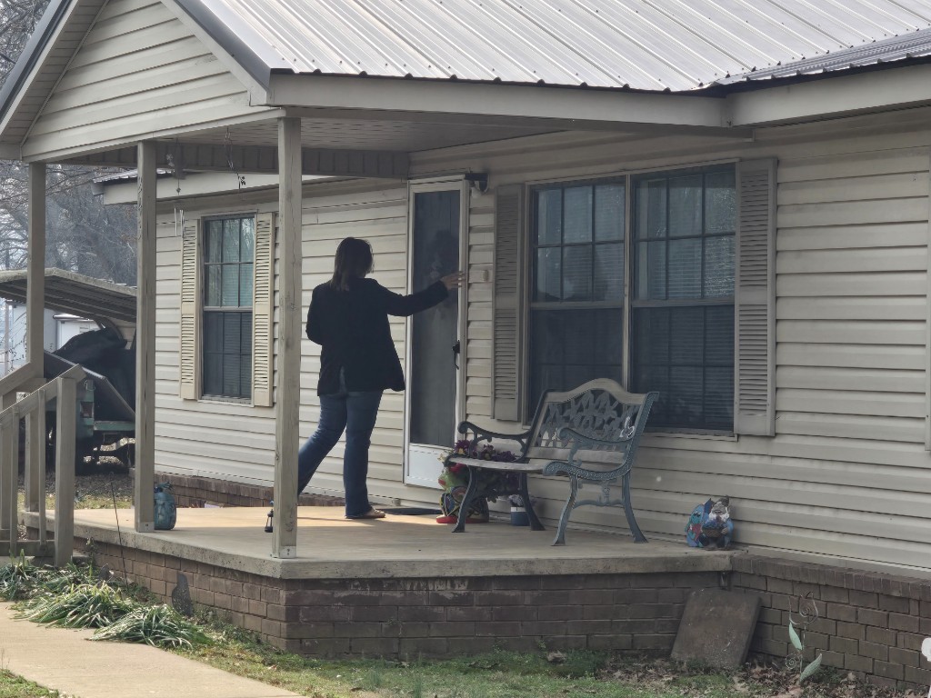 Kelly Grappe for Arkansas Secretary of State — approaches a neighbor on a porch during voter outreach Kelly Grappe, candidate for Arkansas Secretary of State, approaches a neighbor on a porch during voter outreach.